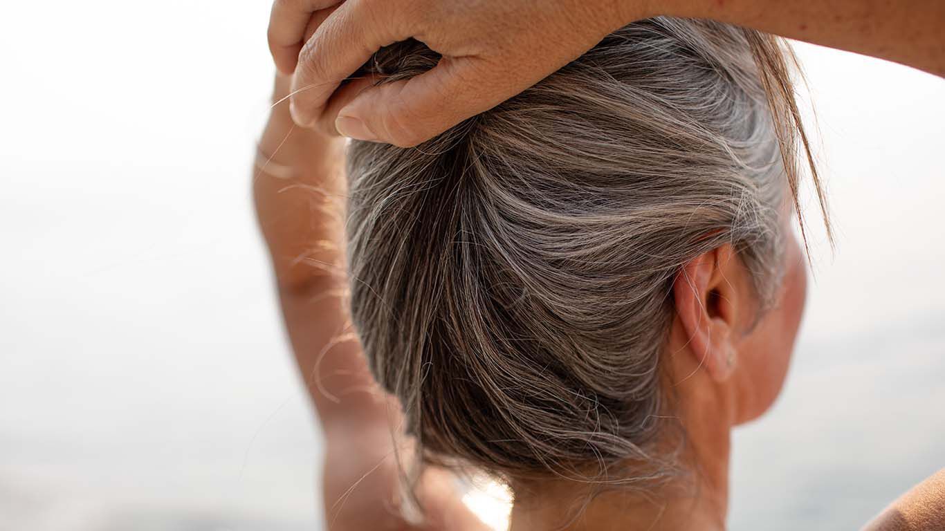 Femme vue de dos, les cheveux relev&eacute;s, au bord de l'eau